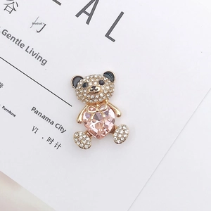 Detail of a gold bear charm with sparkling rhinestones and a pink heart gemstone