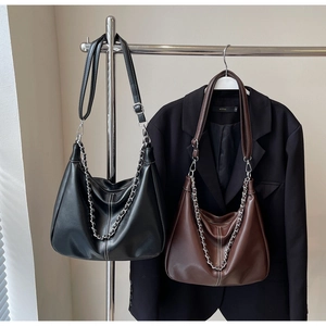 Detail of black and dark brown hobo bags with white contrast stitching and chain straps