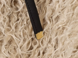 Detail of black leather strap with premium gold metal tip on soft fuzzy fabric