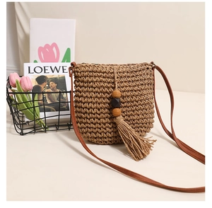 Detail of woven straw bag texture featuring decorative wooden beads and soft tassels