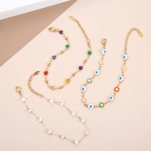 Detail of beaded bracelets with evil eye charms and pearls on gold stainless steel chains
