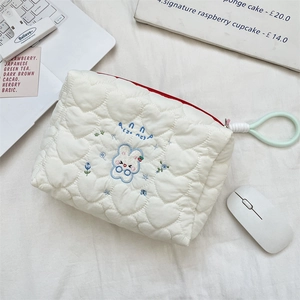 Close-up of quilted heart pattern on white makeup bag with cute rabbit embroidery detail