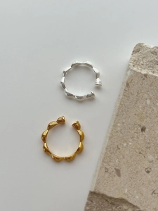 Detail of silver and gold wavy textured open rings on a minimalist stone background