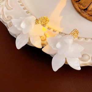 Macro view of vintage white flower earrings with golden center on antique tray