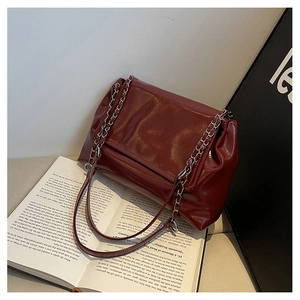 Detail of red patent leather shoulder bag with silver chain strap on a book background