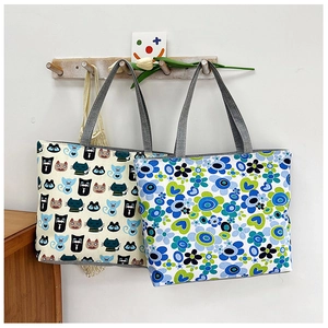 Detail of canvas tote bags with cute cat and floral prints hanging on wooden hooks