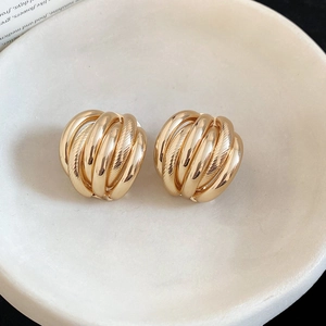 Close-up of golden multi-layered spiral earrings on a ceramic display tray