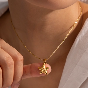 Elegant gold starfish pendant necklace with fine bead chain shown on a model
