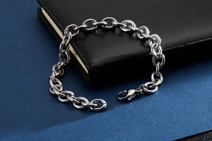 Detail of silver hollow-out oval link bracelet with lobster clasp on a black notebook