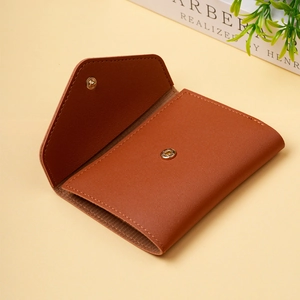 Minimalist brown leather card holder with gold snap button in an open view