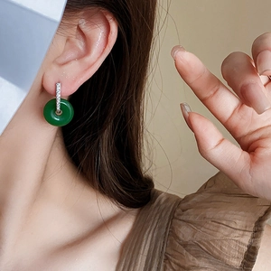 Gros plan d'une boucle d'oreille en jade vert et diamants argentés sur le mannequin