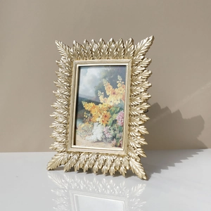Detail of vintage golden resin leaf photo frame with intricate botanical carvings