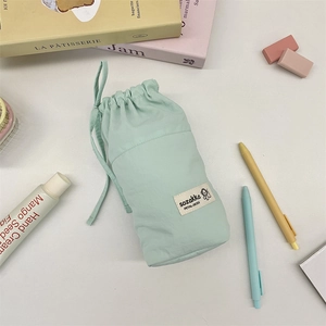Detail of mint green drawstring stationery pouch with woven label and portable loop handle