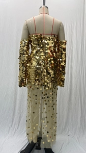 Detail of gold sequins and sheer mesh fabric on the elegant long-sleeved evening gown