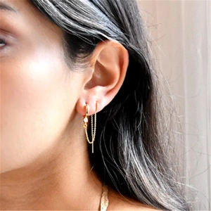 Close-up detail of a delicate gold S925 sterling silver flower fringe chain earring on model