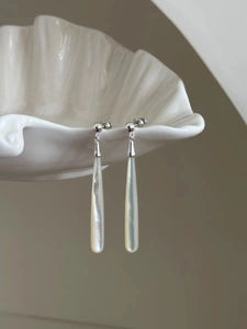 Detailed shot of teardrop earrings with white shell on an elegant shell-shaped tray