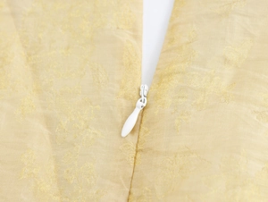 Détail de la fermeture éclair blanche et du tissu jacquard au dos de la robe jaune clair