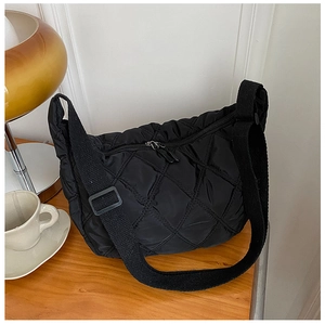 Close-up of black quilted nylon crossbody bag with large capacity on wooden desk