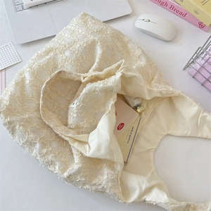 Detailed close-up of cream lace tote bag with 3D floral textures and daily essentials