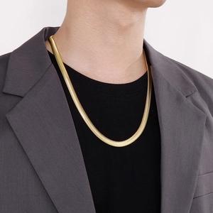 Sleek gold flat snake chain necklace in stainless steel worn with a stylish blazer