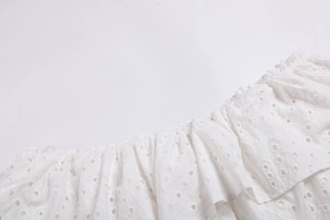 Détail de broderie anglaise blanche et volants sur l'ensemble jupe sirène deux pièces