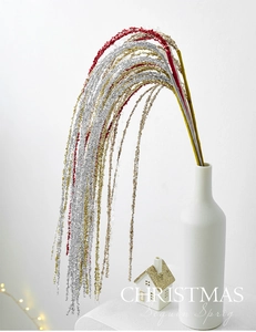 Close-up of sparkling Christmas sequin sprigs in red, gold, and silver in a white vase