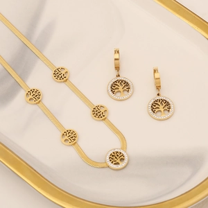Golden Tree of Life jewelry set with zirconia necklace and earrings on a white plate