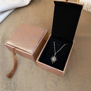 Detail of sunflower pendant necklace with stones in a champagne fringed jewelry box