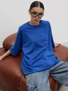Dettaglio di una t-shirt pesante in cotone blu con spalle scese su un divano in pelle