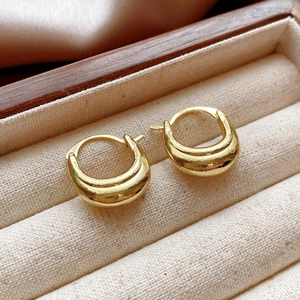 Close-up of chunky gold hoop earrings with a polished finish in a linen jewelry box