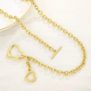 Detailed close-up of golden heart pendant necklace with O-chain and T-bar toggle clasp