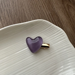 Detailed view of a purple jelly heart hair clip on a minimalist gold metal duckbill clamp