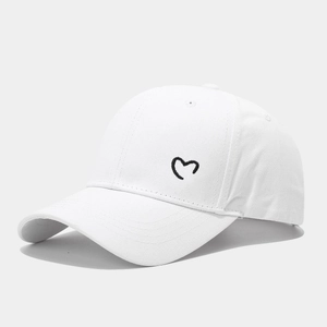 Detail shot of white cotton baseball cap with black heart embroidery and eyelets