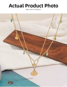 Detail view of double-layer gold necklace with fan shell pendants and blue beads