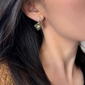 Macro detail of a silver flower drop earring with green zircon and white pearls on a model