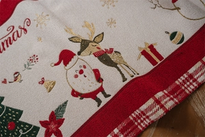 Close-up of Christmas table runner with golden reindeer and tree embroidery detail
