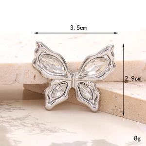 Macro shot of silver bow charm with clear crystals on stone, size 3.5cm by 2.9cm