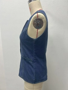Side view of blue denim vest on a beige mannequin showing washed fabric and utility style