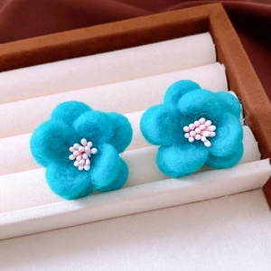 Close-up of blue wool felt flower earrings with delicate soft texture in a jewelry box