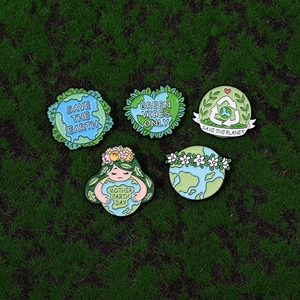 Eco-friendly metal enamel pins with Save the Earth slogans on a green moss background