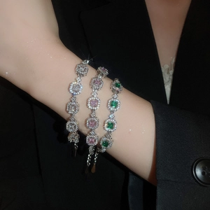 Close-up of three geometric crystal bracelets in silver, pink, and emerald green stones