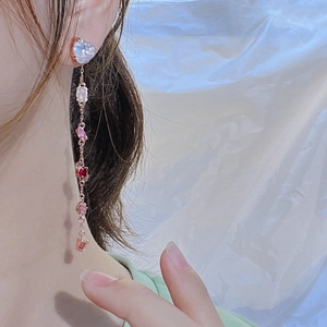 Rose gold tassel earrings with pink and red zircon crystals on a female model