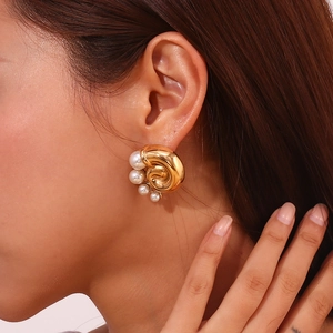 Detail of vintage gold-plated spiral earrings with pearl worn by model