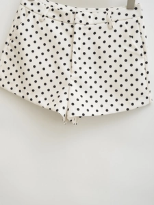 Detailed view of high-waisted polka dot shorts with textured off-white fabric and black spots