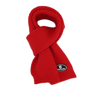 Close-up of red waffle knit scarf with teddy bear patch and soft winter texture