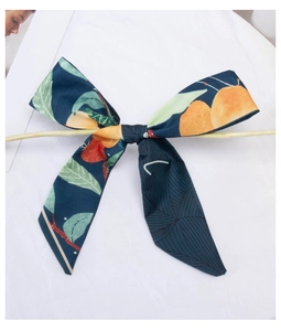 Detail of dark blue fabric bow with orange citrus print on a rustic branch