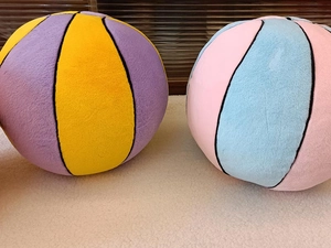 Detail of plush basketball pillows in yellow, purple, pink and blue with stitched segments