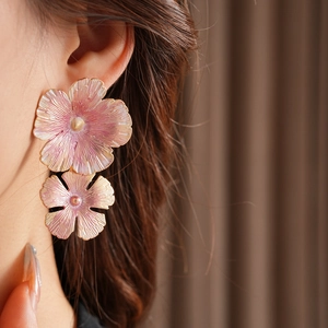 Close-up of pink enamel flower earrings worn by a model with golden pistils