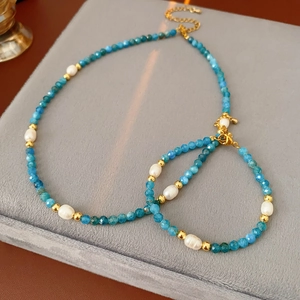 Detail of blue faceted beads and natural pearls on a gold titanium jewelry set