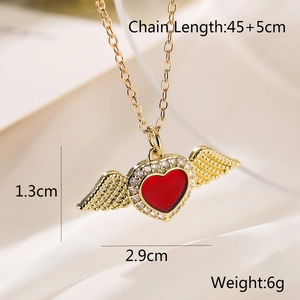 Detailed view of a gold wing pendant with a red heart and dimensions on fabric